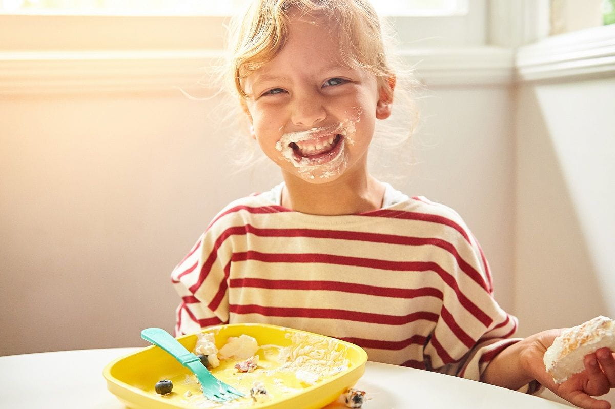 smiling girl with empty plate whipped cream on face